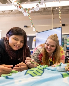Photograph of educator and student smiling while engaging in an activity together.